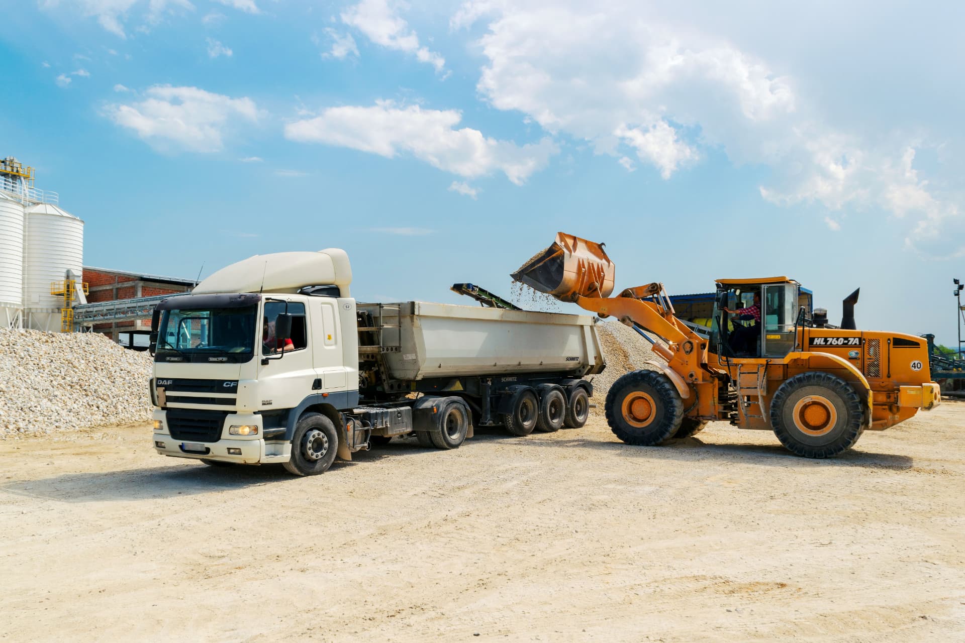 Front-end loader depositing material into a haulage truck at an industrial site