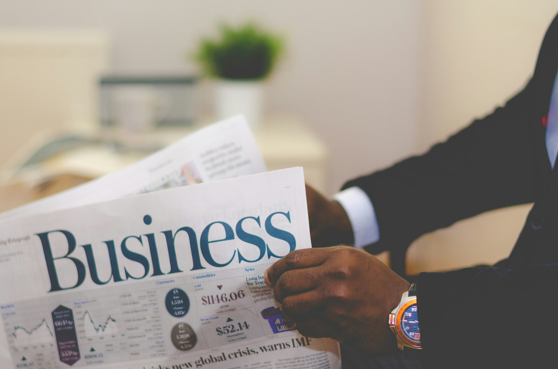 Business professional in a suit reading the business section of a newspaper in an office